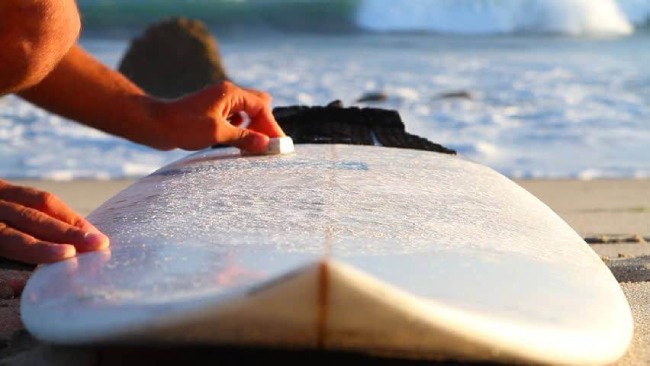 waxing surfboard